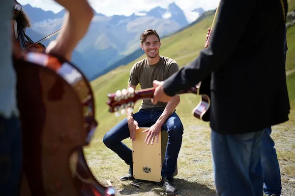 Image d'un homme en train de jouer du Cajon dans la nature avec d'autres magasins